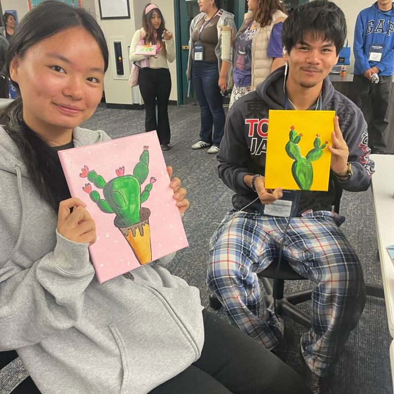 Students holding cacti painting.